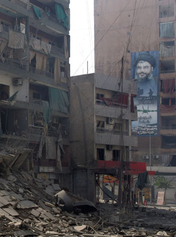A portrait of Lebanese Hezbollah Chief Hassan Nasrallah hangs on a building above the devastated residential area of Beirut's eastern Ruweiss (AFP)