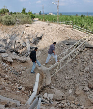Lebanese walk in the rubble of a bridge after an Israeli warplane missile strike destroyed it, in the southern village of Saksakiyeh, south of the port town of Sidon, Lebanon, July 21, 2006 (AP)