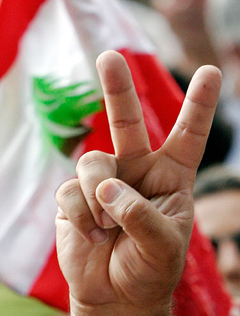 A protester flashes the V sign in front of a Lebanese flag during a demonstration against the Israeli attacks on Lebanon in Paris (AP)