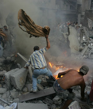 Lebanese rescuers try to extinguish the fire after an Israeli air strike on a building in the southern port city of Tyre, 26 July 2006 (AFP)