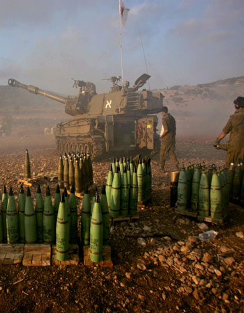 An Israeli artillery unit fires a shell towards Lebanon (R)