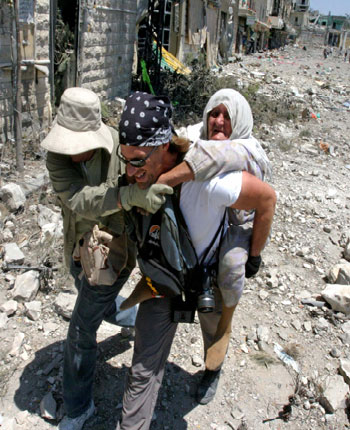 An elderly Lebanese woman is rescued by unidentified foreign journalists in the battered village of Bent Jbeil in southern Lebanon (R)