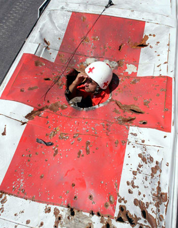 Lebanese Red Cross ambulance worker peers from roof top of ambulance that was bombed at the Red Cross station in Tyre (R)
