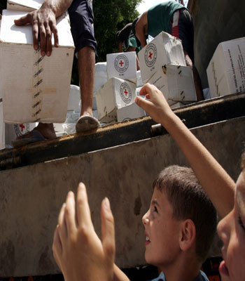 Lebanese refugees receive humanitarian aid from the Red Cross (R)