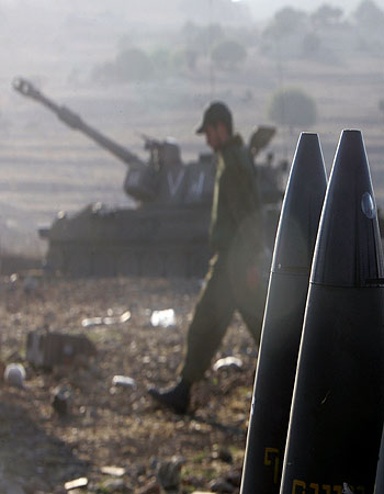An Israeli soldier walks outside a mobile artillery unit (AFP)