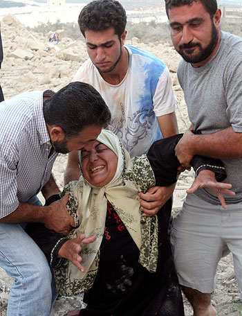 A Lebanese woman is comforted by neighbors and her son after her relatives' house was destroyed by an Israeli air raid (R)