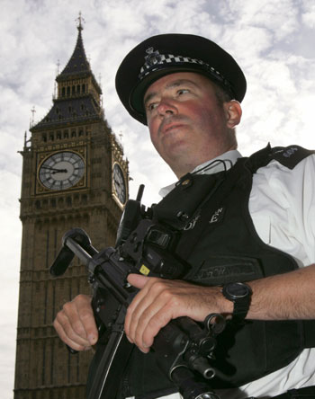 An armed policeman stands outside the Houses of Parliament in London (R)