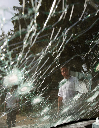 Seen through a shattered windshield, Two Lebanese men look at the wreckage of car that was attacked during an Israeli air raid (AP)