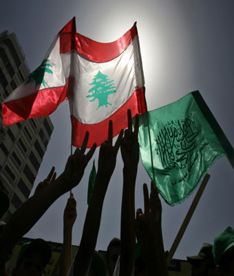 Palestinians hold up Lebanese and Hamas flags during a protest in Gaza City (AFP)