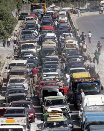 Hundreds of cars with displaced Lebanese returning to southern Lebanon, wait in line to pass a destroyed bridge (AP)