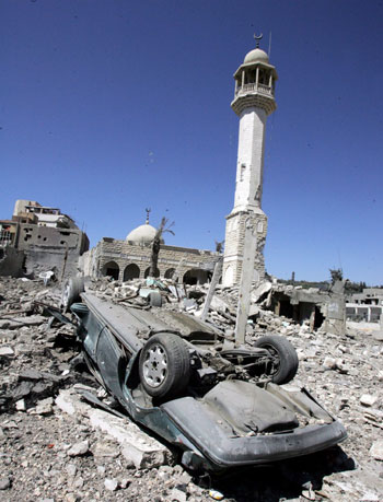 An overturned car sits in front of a damaged mosque damaged by Israeli air strikes east of Tyre (EPA)