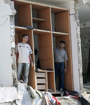 Two men stand in a bedroom closet of their destroyed home in the south Lebanon town of Sarifa, 15 August 2006 (EPA)