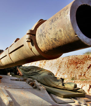 An Israeli soldier sleeps atop a tank parked along the international border with Lebanon, moments after crossing back into Israel, 18 August 2006 (AFP)