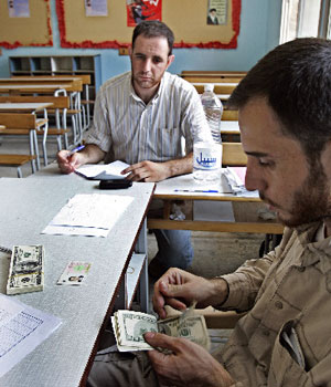 A Lebanese Hezbollah member counts US$ bills to give to residents of a suburb of Beirut who lost their houses during the month-long Israeli offensive on Lebanon, at a school in Bourj el-Barajneh, a southern suburb of Beirut, Lebanon, Aug. 18, 2006 (AP)