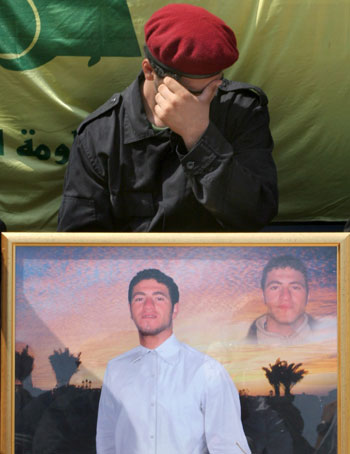 A Hezbollah member holds the portrait of a slain fighter as he mourns during  the funeral (EPA)