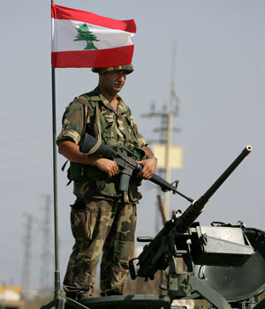A Lebanese soldier stands next to a Lebanese flag on top of an armoured personel carrier at a checkpoint in the southern border town of Kafarkila, Lebanon, Aug. 28, 2006.(AP)