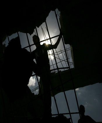 Palestinians inspect damaged house after Israeli forces raided Beit Hanoun (R)