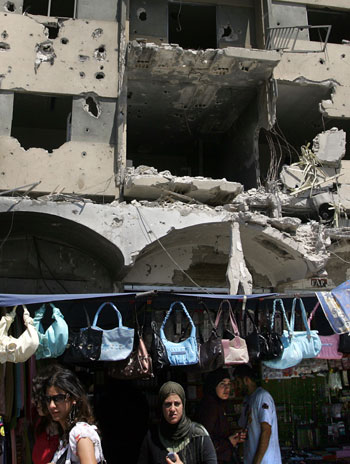 Lebanese shop at a street market located under a heavily damaged building in the southern Lebanese town of Bint Jbeil (AFP)