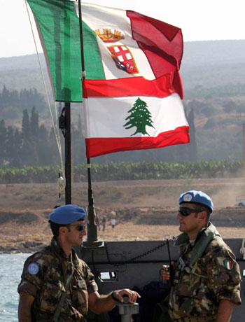 Italian soldiers stand under Lebanese and Italian flags at their base in Naqoura (R)