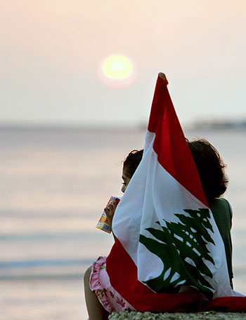 Youths hold a Lebanese flag at a beach in Tyre in southern Lebanon (R)