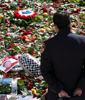 A New York firefighter stands before a reflecting pool filled with flowers and other mementos following the memorial ceremony at the site of the former World Trade Center, 11 September 2006, in New York (EPA)