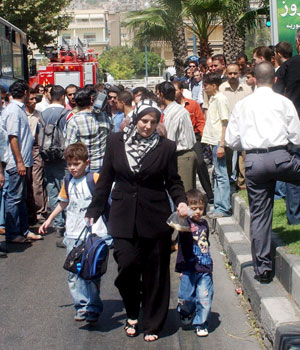 A Syrian mother accompanied by her children who were at a neighboring school when gunmen blew up a car outside the U.S. embassy in Damascus, walks past the crowd near the embassy, 12 September 2006 (EPA)