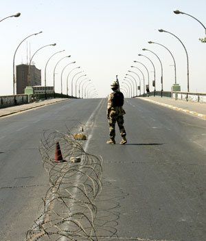 An Iraqi soldier stands on guard in an empty road during a four-hour vehicle curfew for Friday prayers in Baghdad, September 15 2006 (REUTERS)