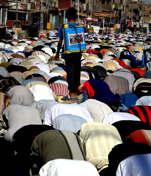 An Iraqi youth sprays water on Shiite Muslim worshippers as they perform the weekly Friday noon prayer at a mosque in Baghdad's Sadr City neighbourhood, 15 September 2006 (AFP)