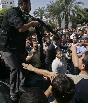 A bodyguard of Palestinian Prime Minister Ismail Haniyeh from Hamas stands on the car carrying Haniyeh as he points his weapon at workers blocking the car during a protest at the parliament building in Gaza City, Sept. 18, 2006.