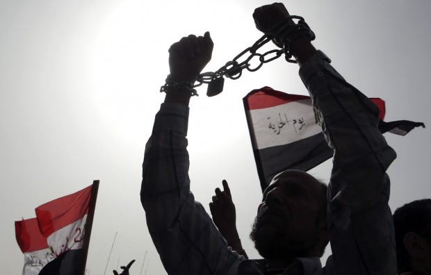 A protester, who opposes Egyptian President Mohamed Mursi, holds up his hands, which are chained together, to symbolise the lack of freedom, as protesters chant slogans during a demonstration against Mursi and members of the Muslim Brotherhood at Tahrir Square in Cairo February 22, 2013. REUTERS/Asmaa Waguih 