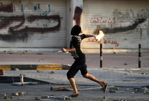 A Bahraini anti-government protester throws a petrol bomb toward riot police firing tear gas during clashes in Daih, Bahrain. (AP)