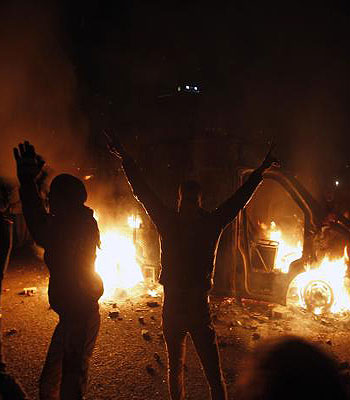 An Egyptian protester flashes victory signs near a police vehicle on fire in Cairo's Tahrir Square on January 28, 2013. (AFP)