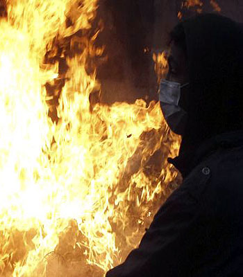 A protester opposing Egyptian President Mohamed Mursi stands in front of fire that they set during clashes with the riot police along Qasr Al Nil bridge, which leads to Tahrir Square, in Cairo. (R)