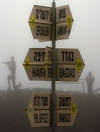 A sculpture of Israeli soldiers standing guard is seen next to a sign for tourists showing the different distances to Jerusalem, Baghdad, Damascus and other locations, at an army post in Mount Bental in the annexed Golan Heights on January 31, 2013. (AFP)