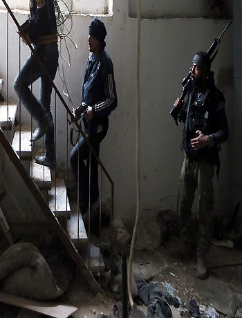 A Free Syrian Army fighter walks in a building destroyed during clashes in the Haresta neighbourhood of Damascus February 1, 2013. (Reuters)