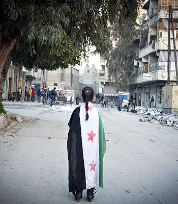 A Syrian girl walks along a street with the pre-Baath Syrian flag across, now adopted by the Free Syrian Army, across her shoulders in the city of Aleppo. (AFP)