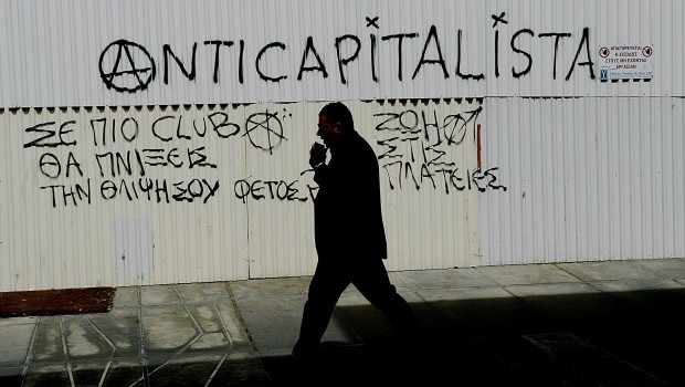 A man passes by anticapitalist graffiti in dowtown of Nicosia, Cyprus, 19 March 2013. The Cyprus parliament is set to vote 19 March on ratification of a one-off tax on bank deposits, following a postponement to allow for consultation.  Source: EPA/FILIP SINGER