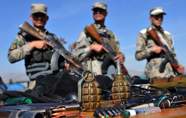 Afghan border police stand guard near seized weapons as they are displayed to the media at a police headquarters in Jalalabad on March 2, 2013. Seven Taliban insurgents have been arrested with their weapons by Afghan border police  during an operation in Ghani khel District of Nangarhar province. AFP PHOTO/ Noorullah Shirzada