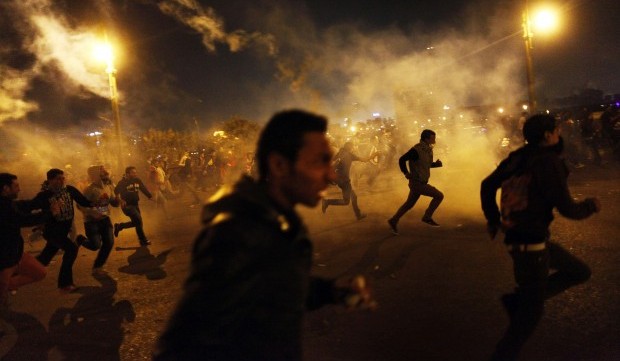 Egyptian protesters run for cover from tear gas fired by riot police during clashes in Cairo, on March 8, 2013. (AFP PHOTO/MAHMUD KHALED