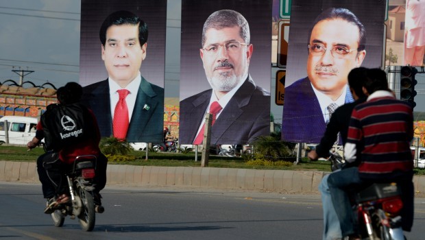 Pakistani motorcyclists ride past billboards featuring portraits of Egyptian President Mohamed Morsi (C), Pakistani President Asif Ali Zardari (R) and Prime Minister Raja Pervez Ashraf along a street in Islamabad on March 17, 2013 Source: AFP PHOTO/Aamir Qureshi