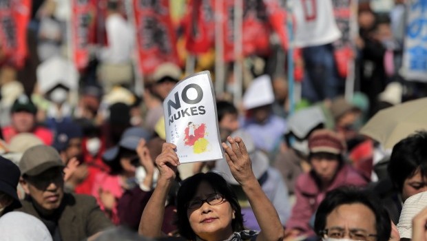 A protester holds aloft an anti-nuclear power plant sign as they stage a rally at a park in Tokyo, Saturday, March 9, 2013. (AP Photo/Itsuo Inouye)