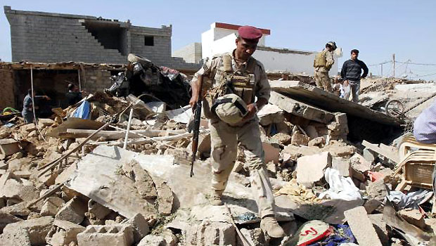 An Iraqi soldier inspects the site of a suicide car bomb attack in Debis, west of Kirkuk March 11, 2013. (R)