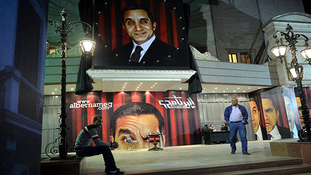 A picture taken on January 22, 2013 shows Egyptians walking past posters of Egyptian satirist Bassem Youssef outside a theatre in Cairo. (AFP)