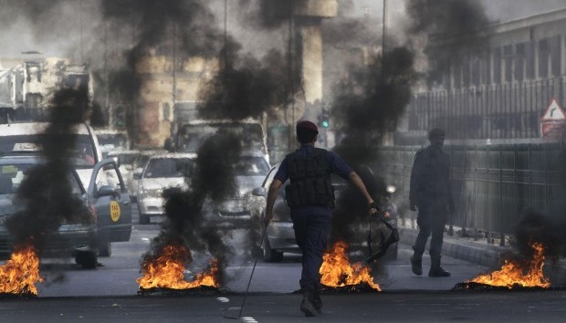 A Bahraini riot police officer walks toward a row of burning tires set alight by Bahraini anti-government protesters on a street in Sehla, Bahrain, on Tuesday, April 9, 2013.  (AP Photo/Hasan Jamali)