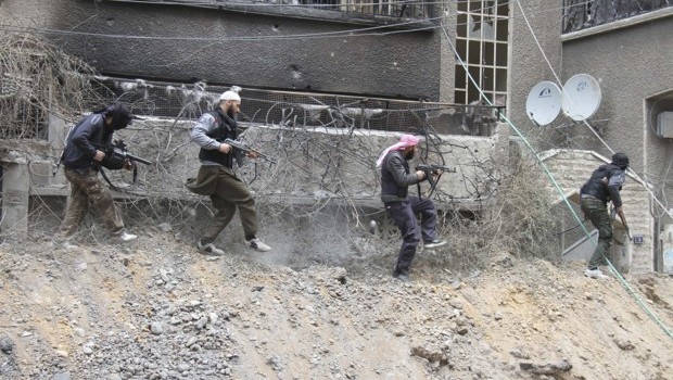 Free Syrian Army fighters carry their weapons as they walk on rubble at the frontline in Sidi Meqdad area in the suburbs of Damascus, April 10, 2013. Picture taken April 10, 2013. (REUTERS/Ward Al-Keswani/Shaam News Network/Handout)