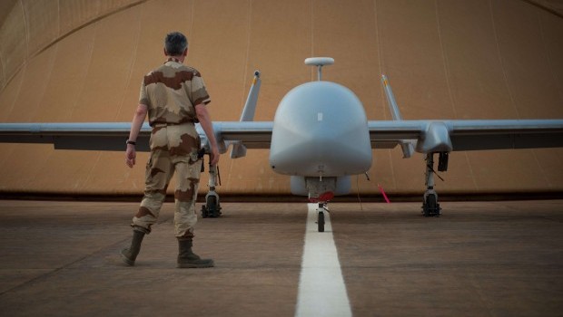 A French soldier of the Serval operation in Mali stands in front of a Harfang drone on April 26, 2013 on the French army base of Niamey. (AFP PHOTO / MARTIN BUREAU)