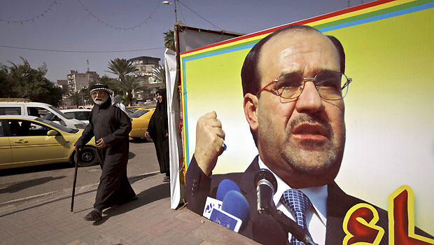 A man walks past a large campaign poster for Prime Minister Nouri al-Maliki in Tahrir Square in Baghdad, Iraq. (AP Photo)