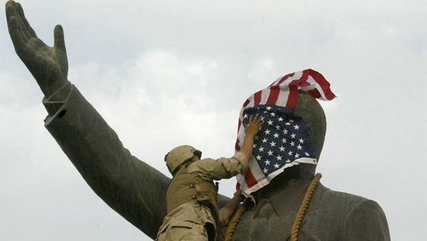 A US Marine covers the face of Iraqi President Saddam Hussein's statue with the US flag in Baghdad's Firdos Square April 9 2003. (AFP Photo)