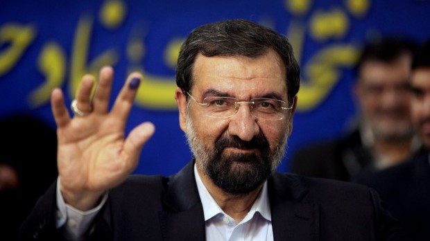 Former chief of Iran's Revolutionary Guard, Mohsen Rezaei, a hopeful for the upcoming presidential election, waves to media, after registering his candidacy, at the election headquarters of interior ministry in Tehran, Iran, Friday, May 10, 2013.
