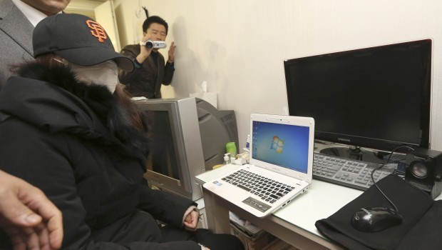 In this photo taken on Dec. 13, 2012, a National Intelligence Service agent covered her face with a mask sits in front of her computers as officers from police and national election commission visit her to collect evidence from her computers at her home in Seoul, South Korea. Source: AP Photo/Im Hun-Jung